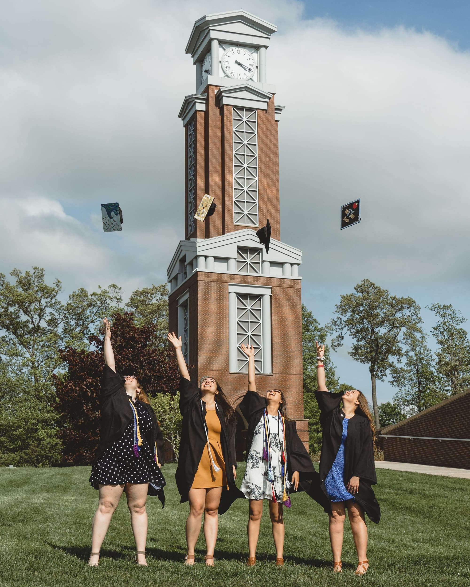Graduates tossing their caps in front of a campus clock tower