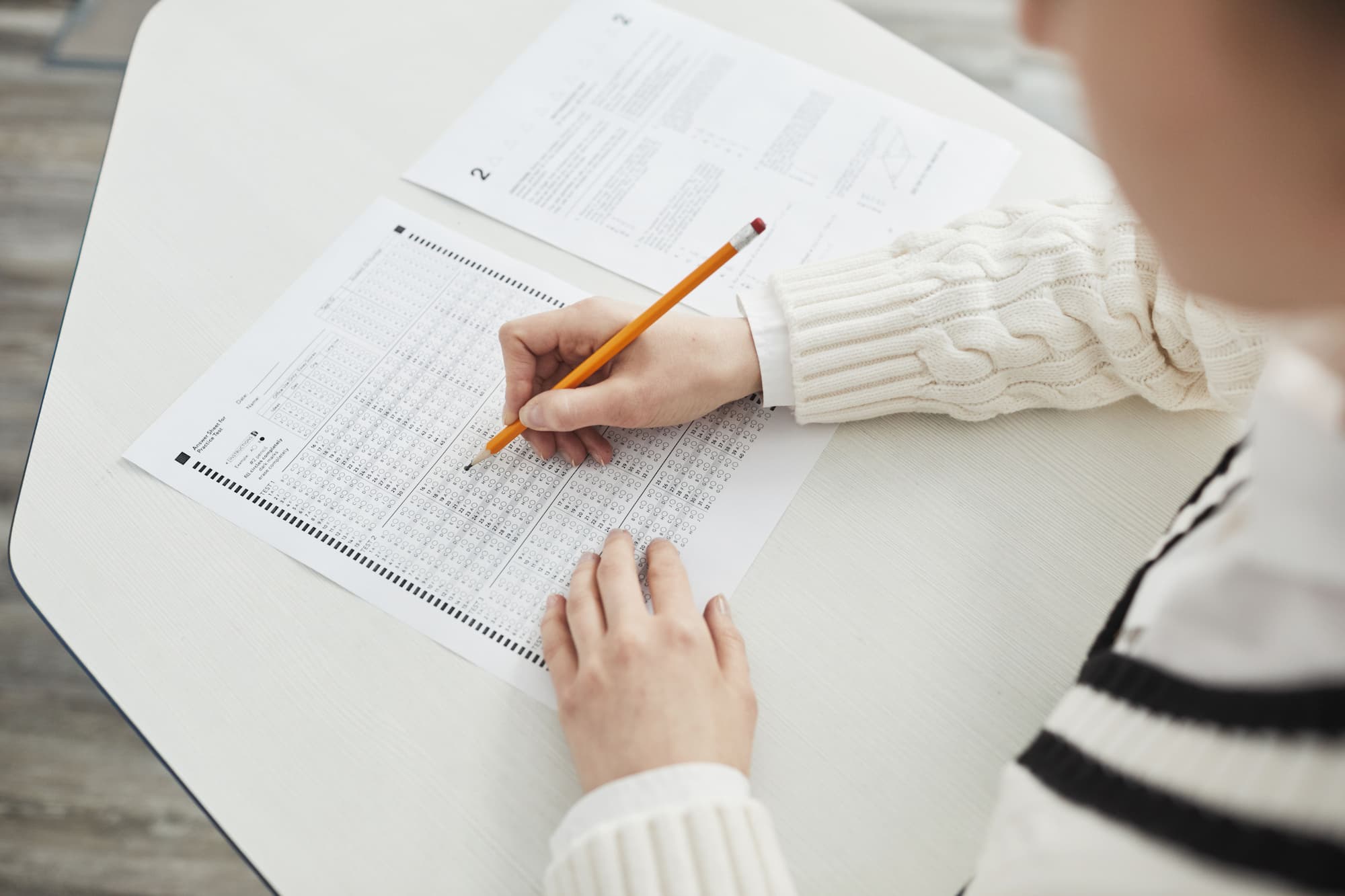 Student filling in a test answer sheet with a pencil